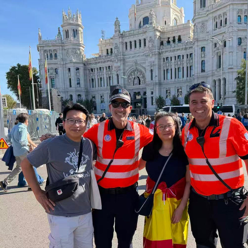 Four people posing together. One man is wearing the faded black Wok and Roll t-shirt from Blue Raven Ministry. Two men are wearing uniforms with reflective strips. The woman is wearing a black top with Spanish flag wrapped around her waist. 