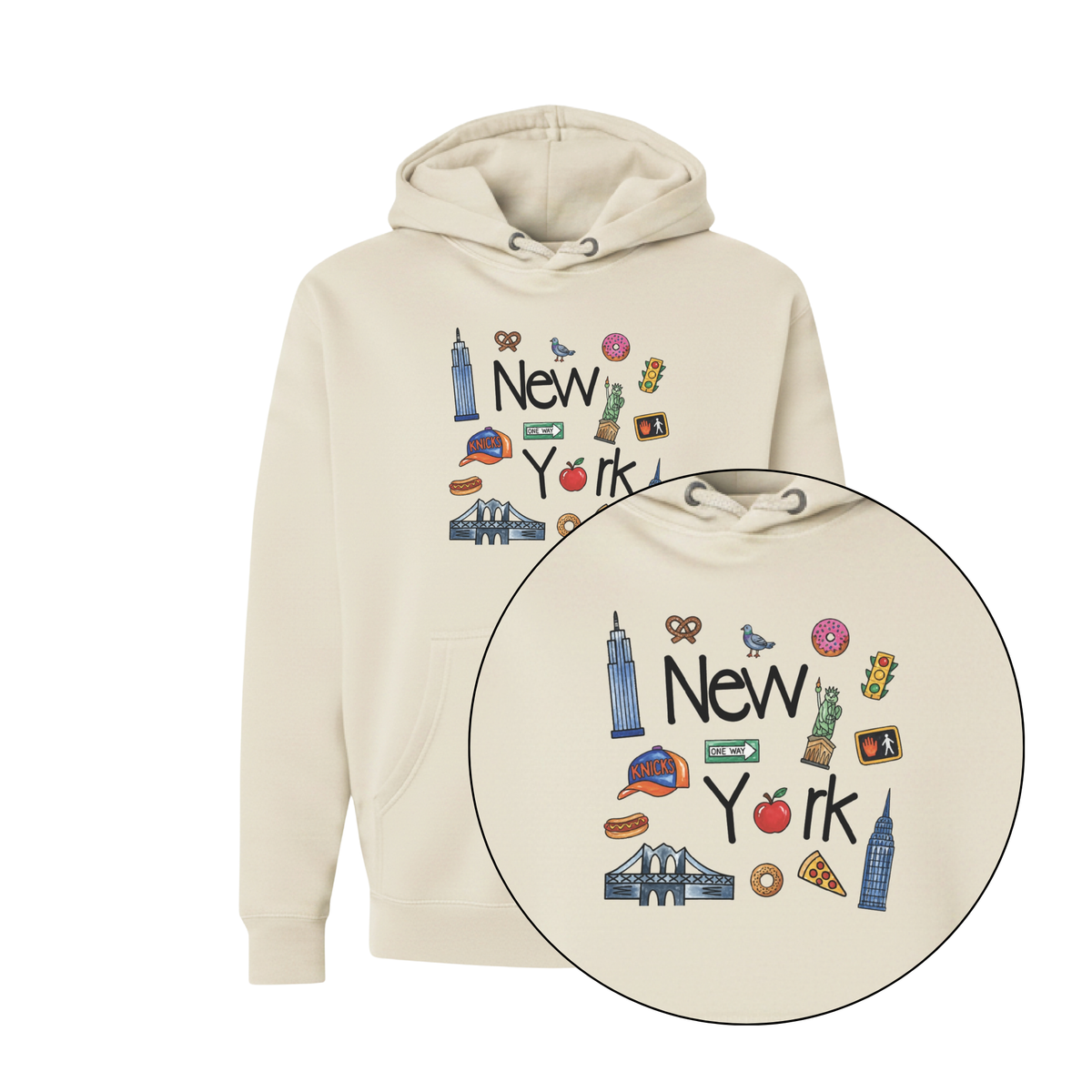 A cream-colored pullover hoodie with a colorful 'New York' graphic on the chest, featuring illustrations of famous landmarks and local icons. A circular inset provides a close-up of the detailed graphic.